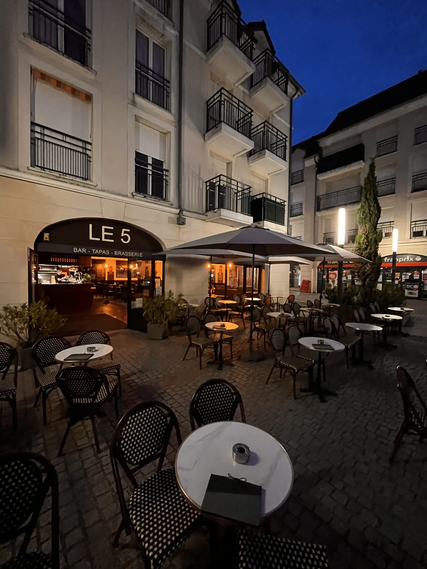 La terrasse du 5 sur la place du village de Sucy-en-Brie au crépuscule
